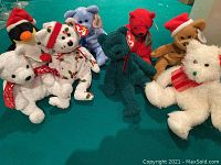 Full view of the 8 assorted Christmas-themed Beanie Babies on a green surface, showing various characters and colors.