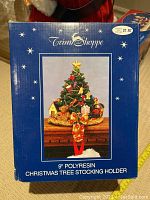 Box of the Christmas stocking holder showing 9 inch polyresin Christmas tree stocking holder with price tag $21.97