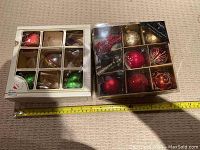 Boxes of Christmas tree ornaments in original packaging, shown with measuring tape indicating size