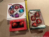 Three boxes of Christmas tree ornaments including 8 multi-colored plastic ornaments, 4 red glass vintage-style ornaments in elves orches box, and 2 red glass red Noel ornaments.