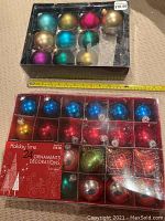 Two boxes of mixed Christmas tree ornaments, one with 9 round ornaments, the other with 24, showing condition and quantity including missing pieces.