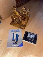 Photo showing large carved wooden horse pen holder, Royal Doulton Collector Handbook and Bryan Nease CD laid out on wooden floor.
