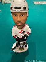 Front view of Michael Peca bobblehead wearing 2002 Team Canada hockey uniform with gold medal on base.
