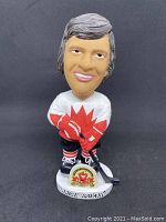 Front view of Serge Savard bobblehead in 1972 Canadian hockey uniform on black background.