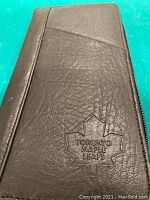 Front side close-up of brown Toronto Maple Leafs carrying case with embossed logo