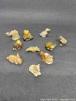 10 ceramic Wade Whimsies animal figurines arranged on a gray surface in two rows, showing variety of animals including camel, dog, duck, rabbit, butterfly, and others.