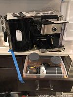 Photo showing the Gevi coffee maker with milk frother and a blender base with cups in a drawer beneath the counter.