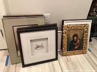 Group of five frames including three empty frames and two framed art pieces