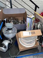 Photo of kitchen appliances including Crock Pot, pots, a boxed item, and bread proofing baskets on a table.