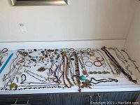 Wide view of the jewelry collection showing necklaces, bangles, bracelets spread out on a white surface.