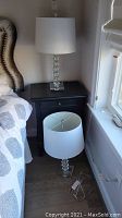 Two lamps displayed in bedroom, one on nightstand and one on floor, both with white drum shades