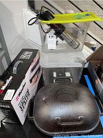 Photo of Anova Precision Cooker immersion circulator in a clear container with yellow lid, Mueller food vacuum sealer box, and cast iron baker with lid in front.
