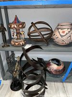 Shelving unit with multiple decorative items: metal sculptures, carousel figurine, pottery vase, and pottery bowl.