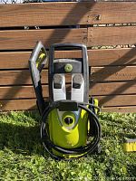 Front view of green and black Sun Joe pressure washer with power cord wrapped around and spray gun attached.