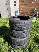 Four studless snow tires stacked outdoors showing tread and sidewalls.