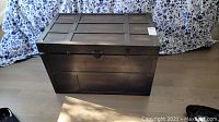 Full front view of wooden storage trunk on floor.