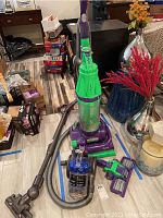 Full view of Dyson City DC26 vacuum cleaner with hose and attachments on floor.