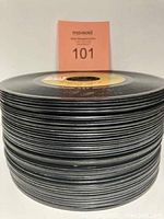 Stack of 50 vintage 45 RPM vinyl records showing the discs stacked horizontally with a small card showing lot number 101.
