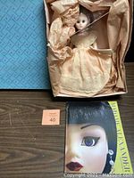 Doll in original box with peach gown and brown tissue paper, including catalog booklet.
