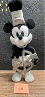 Front view of plush standing on wooden surface. Shows full body and steamboat wheel accessory.