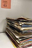 Stack of sleeved 45 RPM vinyl records showing edges and sleeves in various conditions