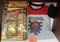 Spider-Man 2 collectibles lot including sealed storybook album with sticker packs and a Marvel t-shirt featuring Spider-Man cartoon graphic.