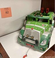 Front angled view of green TMNT sewer truck toy showing front grill, headlights, pull string, and upper light bars.