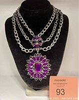 Full view of the triple strand adjustable choker necklace displayed on a black velvet bust with large purple and maroon stone pendant and smaller matching connector.