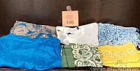 Lot of seven vintage scarves displayed, showing mixed colors and patterns including blue, white with kangaroos, green, beige paisley, and yellow geometric design.