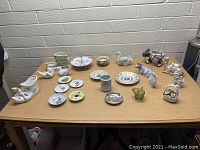 Top down view of assorted vintage ceramic and glass decorative items on wooden table against a brick wall background, showing all pieces in one image.