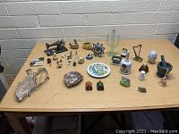 Wide view of all small collectible items on a table, showing various ceramics, figurines, glass, and metal pieces.
