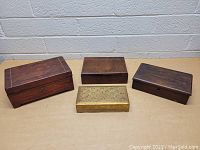 Four vintage wooden boxes arranged on a surface showing tops and sides.