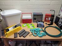 Photo of assorted household and garden items including tools, coolers, hose, and storage organizer on table