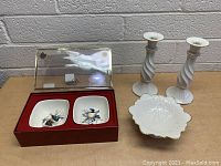 Full view of lot including red box with two Lenox dishes decorated with bird motifs, two white twisted ceramic candle sticks, and one white Lenox pedestal dish with scalloped edges and gold trim.