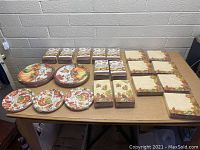 Photo showing multiple stacks of Thanksgiving disposable napkins and several designs of paper plates spread on a table.