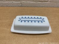 Top view of the vintage Pyrex butter dish showing blue snowflake pattern on white glass lid.