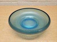 Top angled view of a shallow round blue glass dish bowl showing concave base and wide rim.