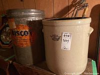 Photo of the 6 gallon stoneware crock and the large Bisocot shortening tin together showing size and condition.