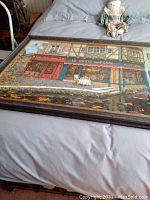Full view of framed print showing colorful shop fronts and canal with water reflections