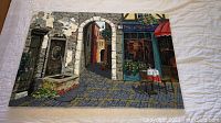 Full view of the signed limited edition print on canvas showing street scene with stone arch and café.