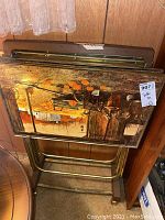 Four vintage folding TV tray tables stacked showing metal frames and artwork tops