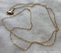 Full view of the yellow gold chain necklace extended on a flat surface, showing the entire length and clasp.