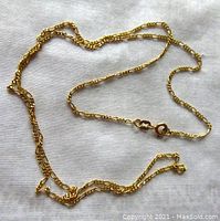 Full view of the 10K yellow gold chain laid out on a white cloth showing the full length and linked style.