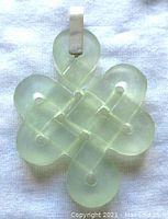 Front-facing photo of light green jade endless knot pendant with sterling silver bail on white background.