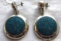 Front view of the pair of large round sterling silver earrings with turquoise stone inlay, showing vibrant blue speckled stones and smooth polished silver frames.