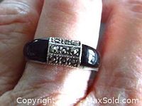 Ring worn on finger showing design and stone setting on top and sides