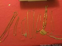 All available vintage jewelry items laid out on red fabric, showing the collections of necklaces, bracelets, and pendants.