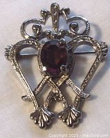 Front view of silver tone Celtic brooch showing textured metal and faceted oval purple glass stone.