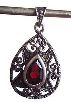 Close-up front view of pear-shaped garnet pendant with openwork marcasite frame hanging on a rod.