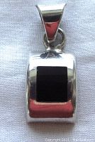 Front-facing view of the sterling silver pendant featuring a rectangular black onyx stone set in a curved silver frame with a large silver bail.